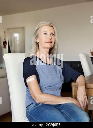 Autriche, Vienne, femme sénior avec bandage adhésif sur le bras assis à la table Banque D'Images