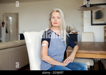 Autriche, Vienne, femme sénior avec bandage adhésif sur le bras assis à la table Banque D'Images