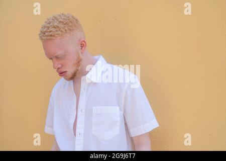 Allemagne, Cologne, Albino homme en chemise blanche contre le mur jaune Banque D'Images