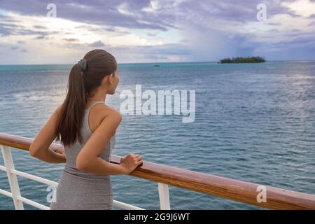 Luxueuse croisière femme de vacances regardant l'île motu de Polynésie française depuis le pont de bateau au coucher du soleil. Détente touristique élégante avec vue sur l'océan à Banque D'Images