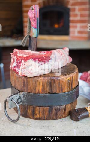 Viande crue sur un pont, un couteau coincé dans la viande. Viande fraîche sur une planche à découper. Gros plan. Banque D'Images