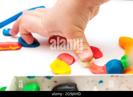 Enfant moules de la pâte à modeler sur la table. les mains à la pâte à modeler. Petite fille est l'apprentissage de l'utilisation de pâte à modeler colorée Banque D'Images