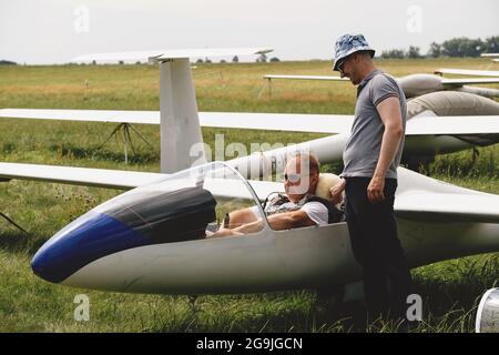 Un club qui s'évolte, prêt pour le vol à bord d'un avion de planeur. Petit sport d'aviation. Deux personnes vérifient le tableau de bord de l'habitacle d'un avion d'époque Banque D'Images