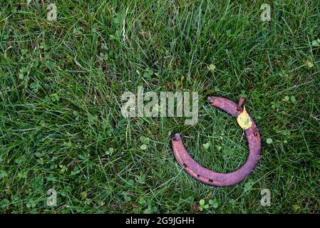 Fer à cheval rouillé sur fond d'herbe - scène rustique dans un style campagnard. Old Iron Horseshoe - symbole de bonne chance et mascotte de bien-être dans un village h. Banque D'Images