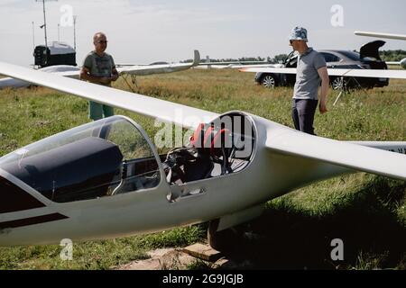 Un club qui s'évolte, prêt pour le vol à bord d'un avion de planeur. Petit sport d'aviation. Deux personnes vérifient le tableau de bord de l'habitacle d'un avion d'époque Banque D'Images