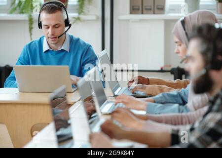 Homme d'affaires sérieux consultant des clients en ligne dans l'environnement de travail au bureau Banque D'Images