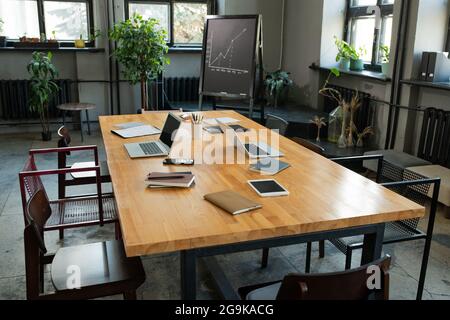 Grande table avec des objets d'affaires et un groupe de chaises autour dans la salle de classe Banque D'Images