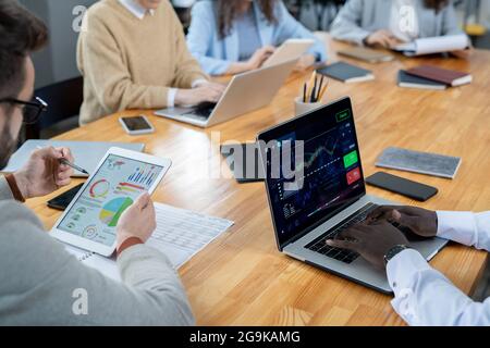 Deux hommes d'affaires multiraciaux utilisant des gadgets mobiles contre trois collègues de travail féminins Banque D'Images