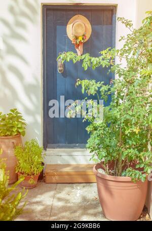 Vieille porte bleue avec chapeau et fleurs de jardin dans une belle lumière ensoleillée avec rétro vintage. Image en tons Banque D'Images