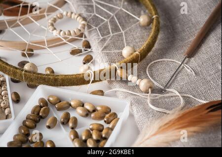 Assemblage du capteur de rêve fait main. Composition à la maison du symbole traditionnel des Indiens d'Amérique, tribal. Gros plan de perles de bois Banque D'Images