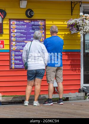 Le couple âgé est debout dans la rue et regarde le menu de la cafétéria à l'extérieur. Fisherman Wharf, Victoria, C.-B., Canada-juillet 23,2021. Photo de rue, t Banque D'Images