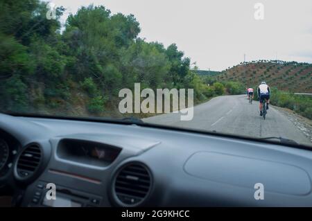 Conduite lente derrière les cyclistes sur la route de campagne sinueuse. Vue de l'intérieur de la voiture Banque D'Images