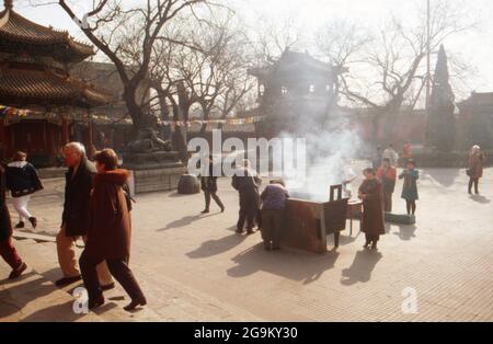 Gläubige opfern Weihrauch vor dem Yonghe Tempel à Pékin, Chine 1998. Croyants tirant des bâtons parfumés à l'entrée du temple Yonghe à Beijing, Chine 1998. Banque D'Images