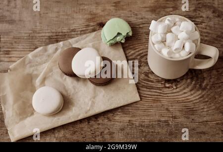 café avec guimauves et macarons sur un plateau en bois, dans le lit. Cadre esthétique. Desserts au lit. Chocolat chaud avec guimauves. Banque D'Images