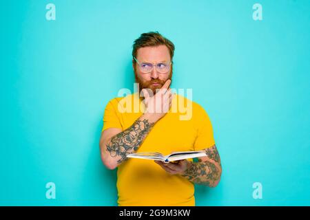 Un homme avec un t-shirt jaune lit un livre Banque D'Images