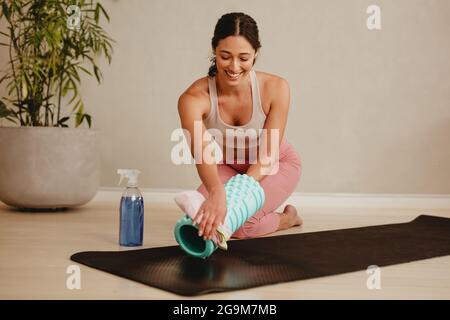 Femme heureuse nettoyant rouleau d'exercice et tapis avec désinfectant après l'entraînement sportif dans un club de santé. équipement d'entraînement désinfectant et nettoyant pour les membres du gymnase Banque D'Images