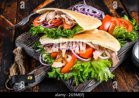 Gyros grecs enveloppés de pain pita avec des légumes et de la sauce. Arrière-plan en bois sombre. Vue de dessus Banque D'Images