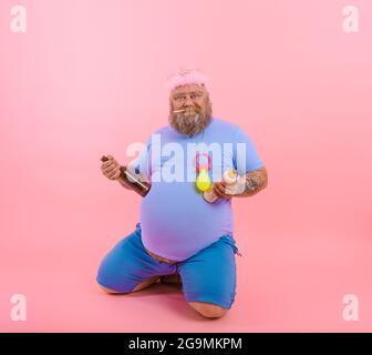 FAT Happy man agit comme un bébé heureux mais boit de la bière Banque D'Images