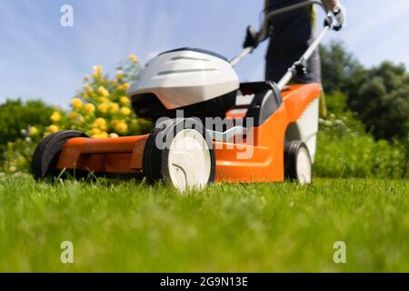 Une femme jardinière tond l'herbe avec le coupe-herbe, vue de dessous Banque D'Images