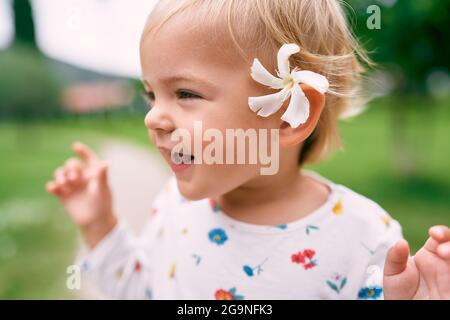 Petite fille drôle avec une fleur derrière son oreille. Portrait Banque D'Images