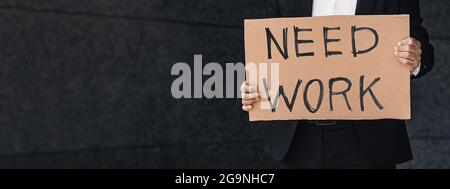 Plus d'argent sur le concept de quarantaine. Un employé de bureau tenant une affiche en carton portant l'inscription « Need Work » Banque D'Images