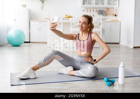 Le blogueur de modèle de forme physique fait des photos pour les réseaux sociaux, un appareil moderne pour le travail et l'entraînement à la maison Banque D'Images