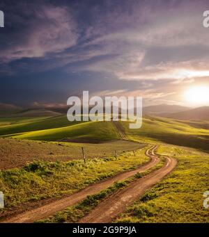 un long et sinueux chemin rural traverse les collines au coucher du soleil Banque D'Images