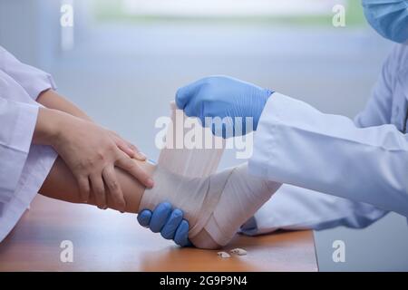 Pieds tenant avec le médecin, le médecin analyse et explique la douleur dans les os des pieds du patient.Docteur le traumatologue examine la jambe examinée à t Banque D'Images
