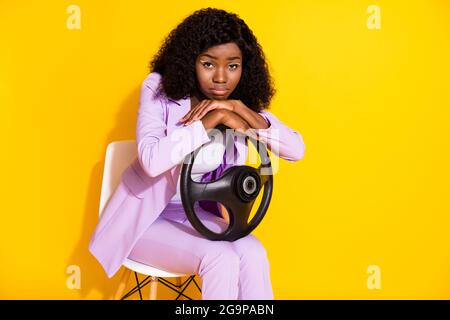 Photo de jeune malheureux contrarié triste afro femme d'affaires assis chaise tenir le volant isolé sur fond jaune Banque D'Images