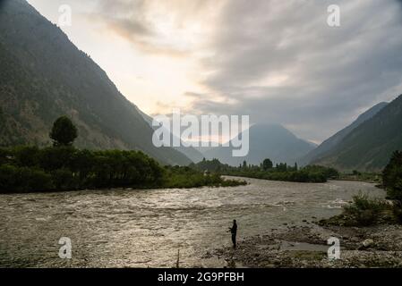 Silhouette d'un homme qui pêche dans la rivière Kishanganga en début de matinée à Dawar. Gurez se trouve le long de la ligne de contrôle (LOC) dans la partie nord du Cachemire. La vallée de Gurez a été la clé de la route de la soie de l'Europe à Kashgar en Chine et demeure de la tribu de Dard parlant shina, mais elle n'a été ouverte au monde qu'en 2007. Avant 2007, Gurez n'était ouvert qu'à l'époque coloniale lorsque les voyageurs venaient explorer la vallée. La ligne de contrôle traverse maintenant la vallée idyllique, séparant les dards de leurs frères Indo-aryens à Gilgit, Chilis et Astore, au Pakistan. (Photo par Idrees Abbas/SOPA im Banque D'Images