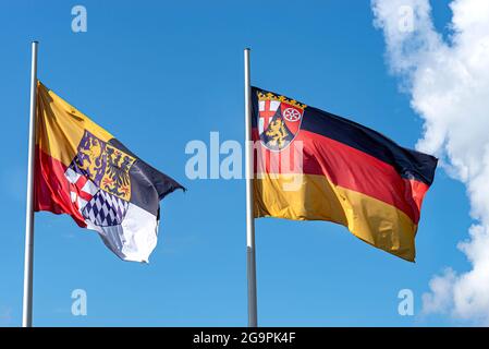 Drapeau allemand sur un mât agitant dans le vent avec les armoiries de l'état de Rhénanie-Palatinat et de la ville de Loreley. Banque D'Images
