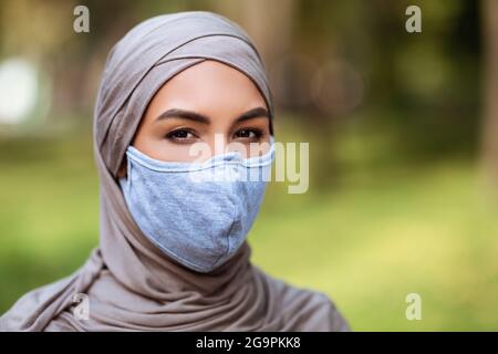 Femme musulmane dans le hijab portant un masque médical à l'extérieur Banque D'Images