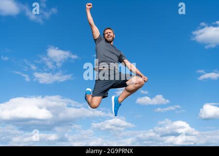 un homme musclé sautant dans des vêtements de sport en plein air sur fond de ciel, succès Banque D'Images