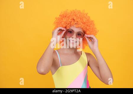 drôle d'enfant dans la perruque de clown. s'amuser. enfant porter des lunettes de soleil et un maillot de bain. Banque D'Images