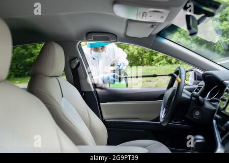 Homme dans une combinaison de noisettes nettoie automatiquement. Éliminer les bactérias, les virus et les infections pendant le transport Banque D'Images