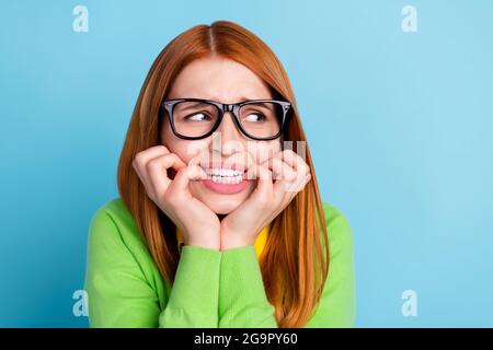 Portrait d'une fille à cheveux rouges effrayée et désespérée attrayante attendant de mauvaises nouvelles mordant des ongles isolés sur fond bleu vif Banque D'Images