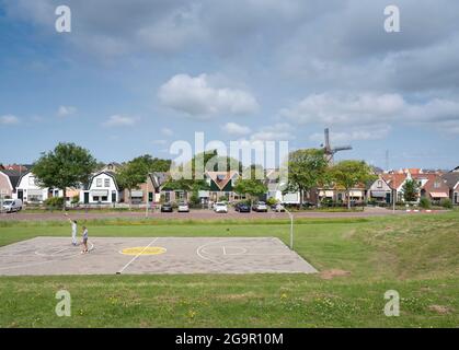 les gens jouent au basket-ball dans le village hollandais avec le moulin à vent d'oudeschild sur l'île hollandaise de texel en hollande Banque D'Images