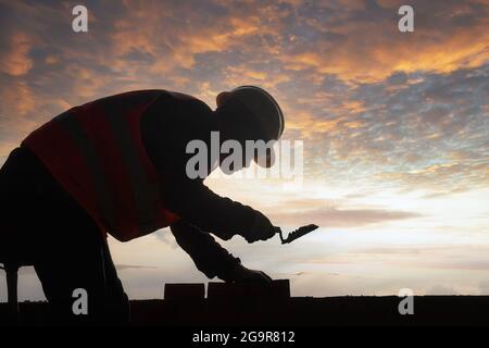 Silhouette ouvrier de maçon de construction, ouvrier de construction pose des briques et de construction barbecue dans le site industriel. Banque D'Images