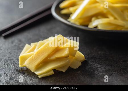 Tranches de pousses de bambou en conserve sur table noire. Banque D'Images