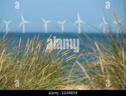 Scroby Sands Wind Farm dans la mer du Nord au large de la côte est de Norfolk au loin, photographié à travers les dunes de sable herbeuses de Caister on Sea. Banque D'Images