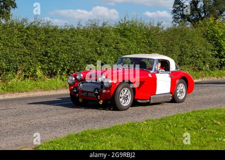 1966, 60s rouge blanc Austin Healey 2912cc véhicule à essence en route vers Capesthorne Hall classique de juillet spectacle de voiture, Cheshire, Royaume-Uni Banque D'Images