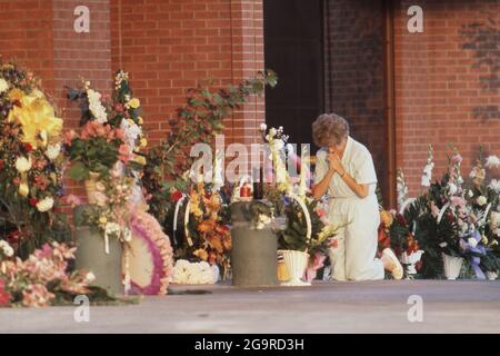 Killeen Texas USA, octobre 1991: La femme s'agenouille dans les prières parmi les fleurs laissées en mémoire des victimes d'une fusillade de masse à la cafétéria de Luby à Killeen. Le 16 octobre. George Hennard, un habitant de 35 ans de Killeen, s'est écrasé un ramassage dans le restaurant et a tué 23 dîners et membres du personnel avant de se tuer. ©Bob Daemmrich Banque D'Images