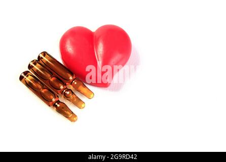 Trois ampoules médicales et un cœur rouge. La composition est isolée sur un fond blanc. Banque D'Images