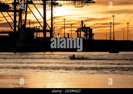 Scooter aquatique qui traverse une baie au coucher du soleil. Banque D'Images