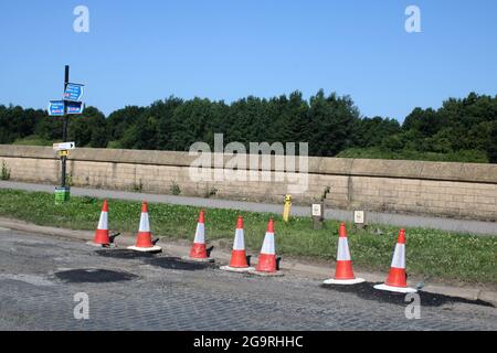 Cônes de circulation où des travaux de réfection sont en cours. Les vieux pavés qui étaient autrefois la surface de la route sont visibles là où l'ancien tarmac a été enlevé. Banque D'Images