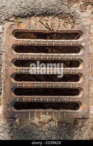 Grille d'un petit drain sur le côté d'une route. Banque D'Images