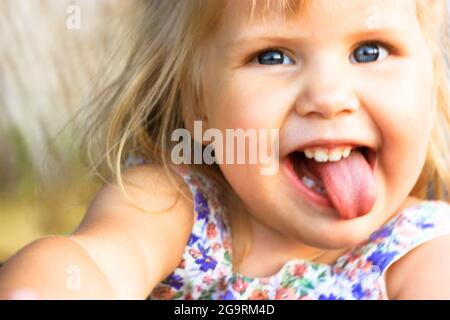 Bebe Avec L Expression Drole Et La Langue Dehors Est Assis Sur Les Genoux De Mere Photo Stock Alamy