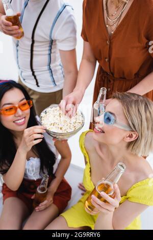 joyeux amis multiculturels boire de la bière et manger du pop-corn pendant la fête d'été Banque D'Images