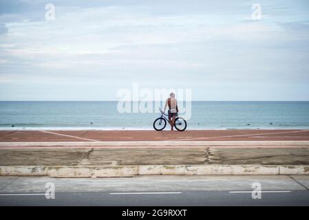 cycliste se tenant sur la rive et regardant la mer Banque D'Images