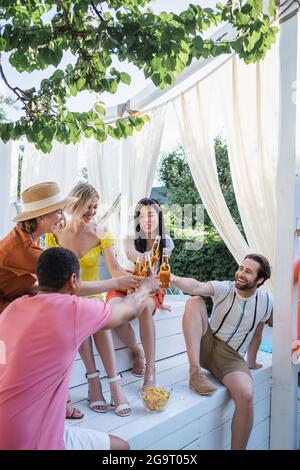 Les jeunes toaster avec de la bière près des chips dans le patio Banque D'Images